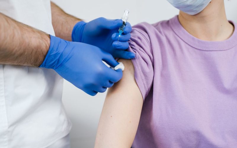 Ärztin verabreicht einer Patientin eine Schutzimpfung in den Oberarm